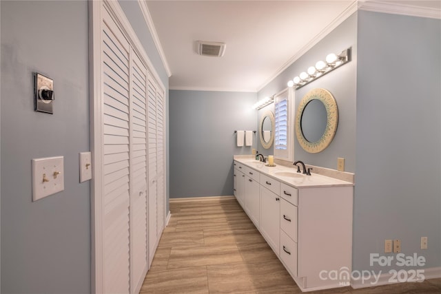 bathroom with double vanity, visible vents, ornamental molding, a sink, and a closet