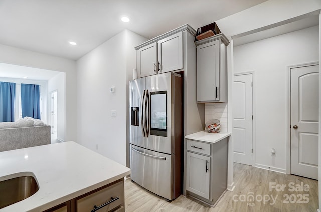 kitchen featuring light wood-style flooring, gray cabinets, stainless steel refrigerator with ice dispenser, and backsplash