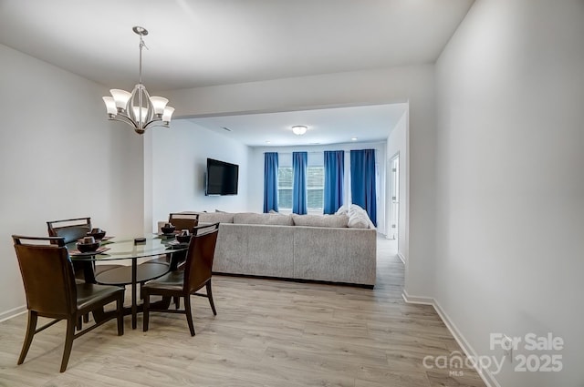 dining room featuring light wood-style floors, a chandelier, and baseboards