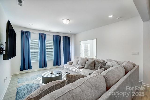 living room featuring baseboards, visible vents, wood finished floors, and recessed lighting