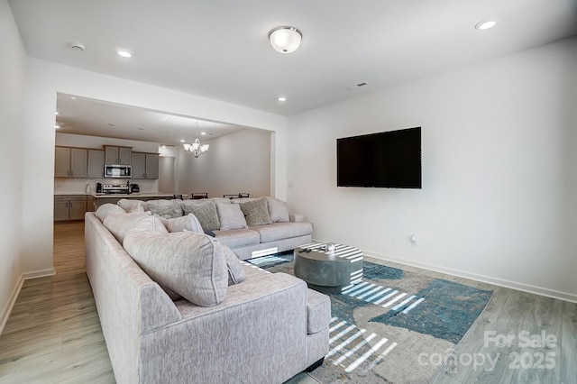 living area featuring a chandelier, recessed lighting, light wood-type flooring, and baseboards