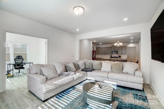 living area with recessed lighting, light wood-style flooring, baseboards, and an inviting chandelier