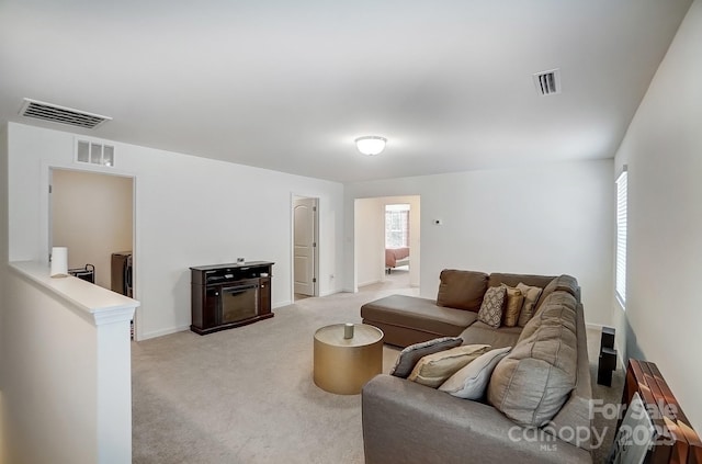 living area with light carpet, visible vents, and washer and clothes dryer