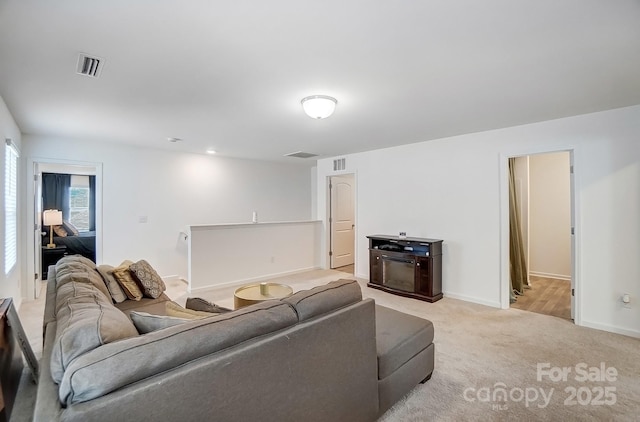 living room with baseboards, visible vents, and light colored carpet