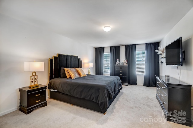 bedroom with baseboards and light colored carpet