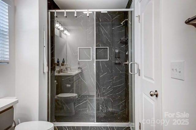 bathroom featuring toilet, a marble finish shower, and vanity