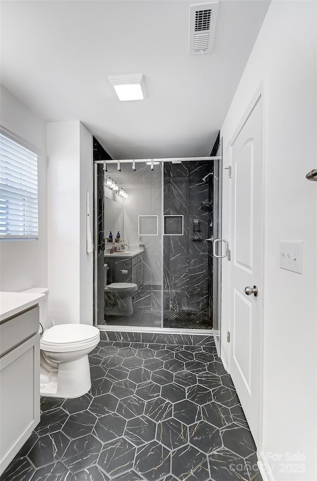 bathroom with toilet, a stall shower, vanity, and visible vents