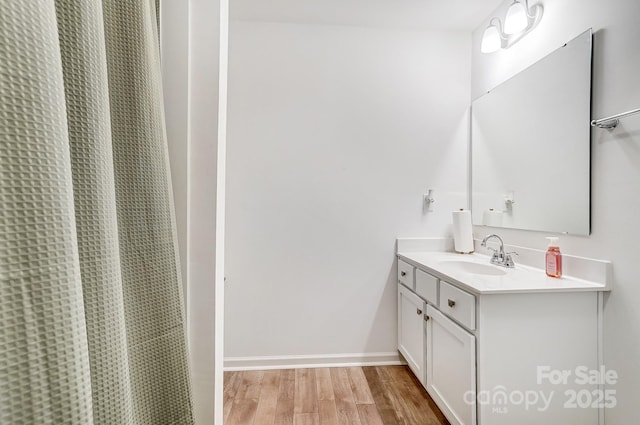 full bath with a shower with shower curtain, wood finished floors, vanity, and baseboards