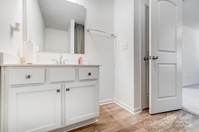 bathroom featuring wood finished floors, vanity, and baseboards