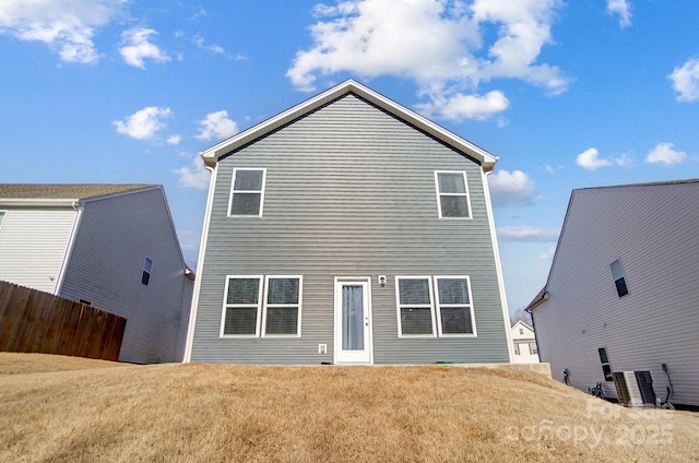 rear view of property featuring central AC unit, a lawn, and fence