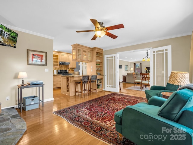 living room featuring baseboards, ornamental molding, a ceiling fan, and light wood-style floors