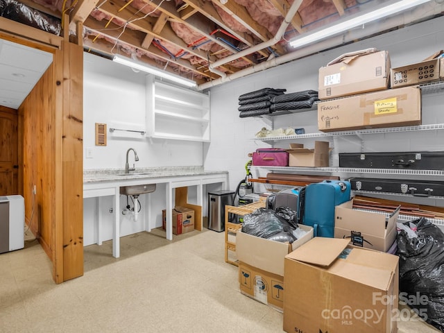 unfinished basement with concrete block wall, visible vents, a sink, and tile patterned floors