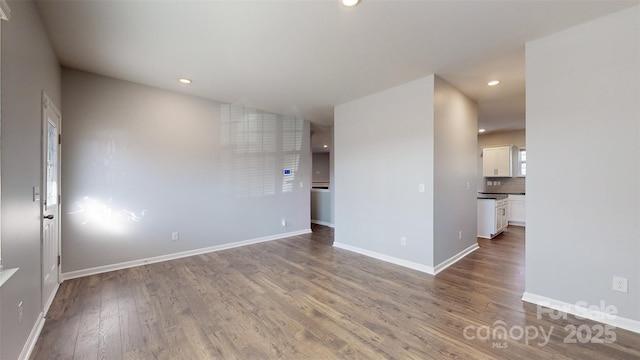 empty room featuring recessed lighting, wood finished floors, and baseboards