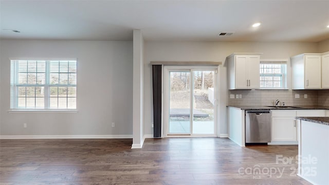 kitchen featuring baseboards, white cabinets, wood finished floors, stainless steel dishwasher, and backsplash