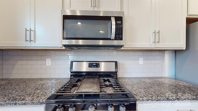 kitchen with gas stove, white cabinets, and stainless steel microwave