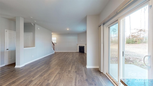 unfurnished living room featuring stairway, dark wood-style flooring, a fireplace with flush hearth, and baseboards