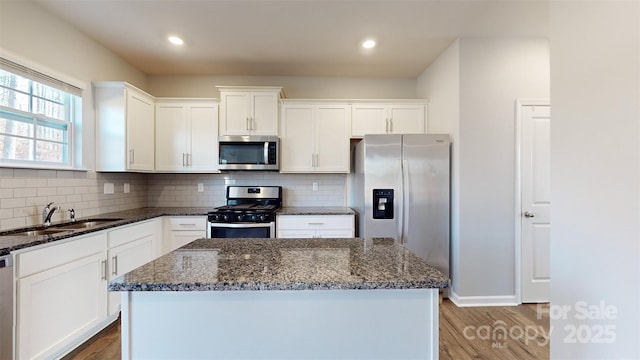 kitchen with white cabinetry, appliances with stainless steel finishes, a sink, and a center island