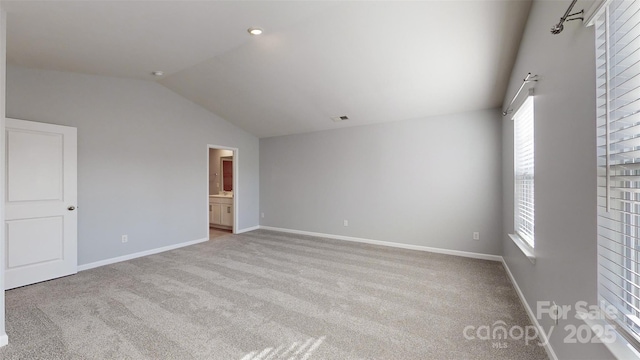 interior space with lofted ceiling, light carpet, visible vents, and baseboards