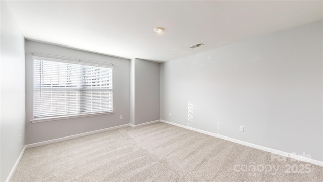 empty room with baseboards, visible vents, and light colored carpet