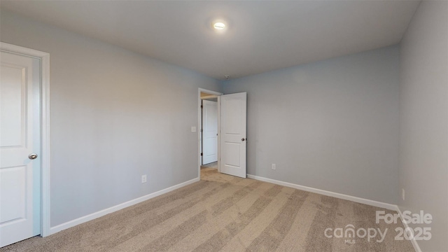 unfurnished room with baseboards and light colored carpet