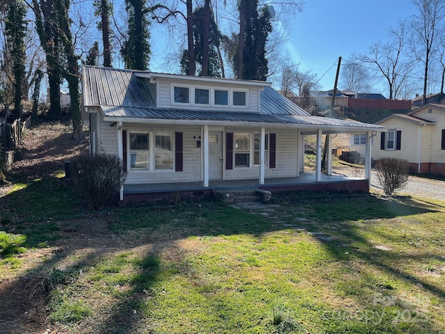 bungalow-style house with covered porch, metal roof, a front lawn, and a carport