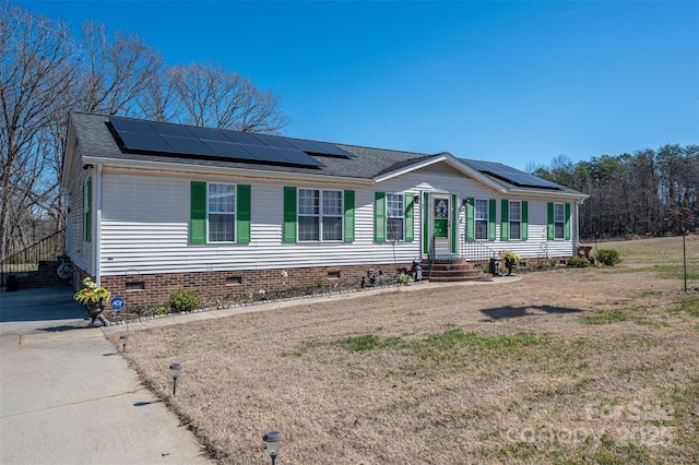 view of front of house featuring roof with shingles, solar panels, crawl space, driveway, and a front lawn