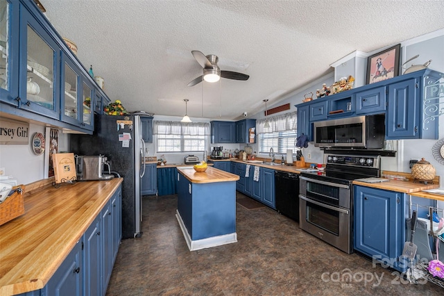 kitchen with butcher block countertops, blue cabinets, a kitchen island, and appliances with stainless steel finishes