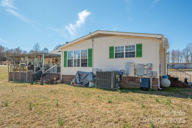 rear view of house with a lawn and central air condition unit