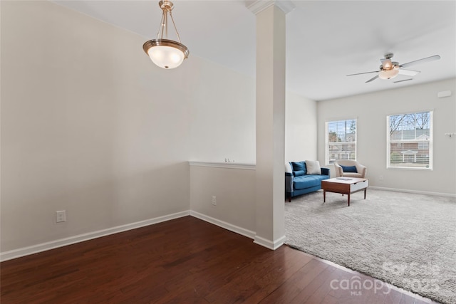 living area featuring baseboards, wood finished floors, a ceiling fan, and ornate columns