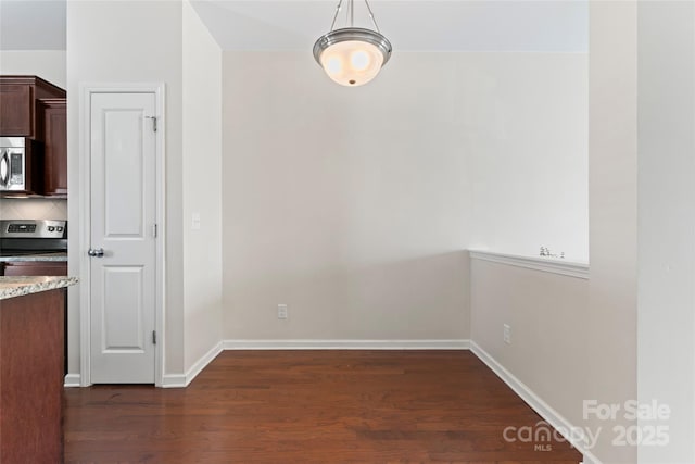 unfurnished dining area featuring dark wood finished floors and baseboards