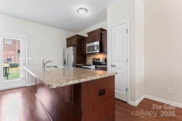 kitchen featuring a kitchen bar, dark wood finished floors, appliances with stainless steel finishes, and a sink