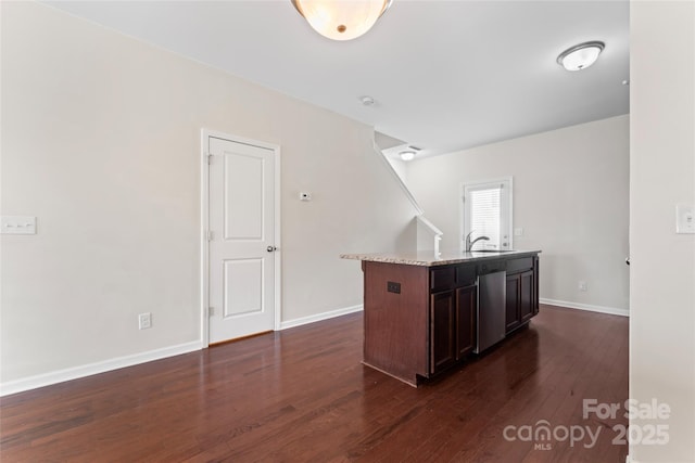 kitchen with a kitchen island with sink, a sink, stainless steel dishwasher, baseboards, and dark wood-style flooring