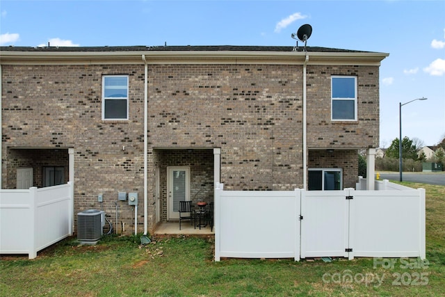 back of house with brick siding, a patio area, cooling unit, and fence