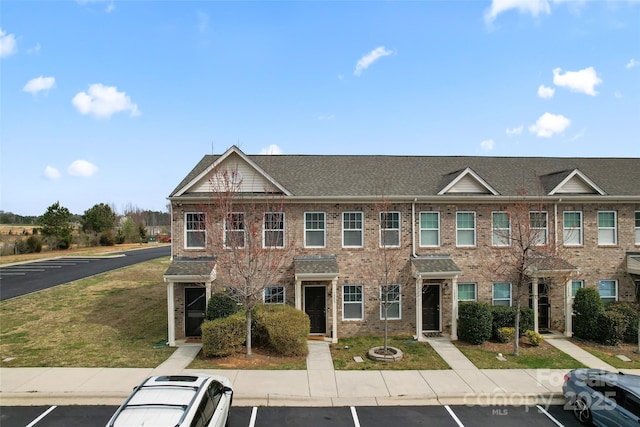 townhome / multi-family property featuring uncovered parking and brick siding