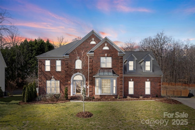 view of front facade with brick siding, a front yard, and fence