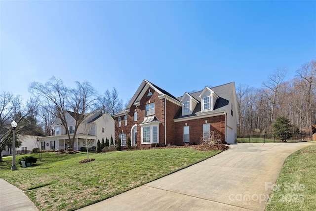 traditional-style home featuring driveway, brick siding, an attached garage, fence, and a front yard