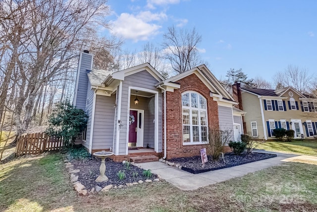 view of front of house featuring brick siding, a chimney, fence, a garage, and a front lawn