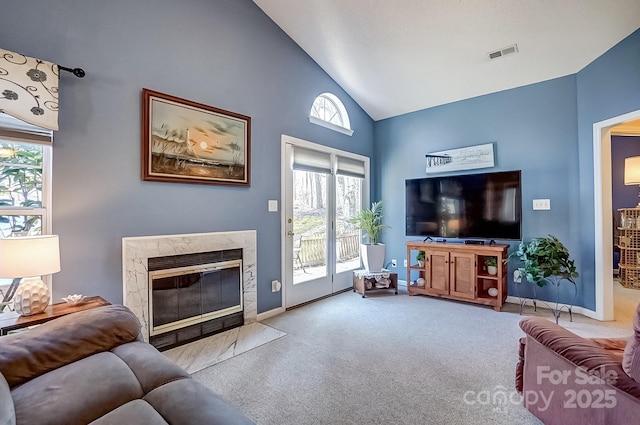 living room featuring light colored carpet, visible vents, a high end fireplace, high vaulted ceiling, and baseboards