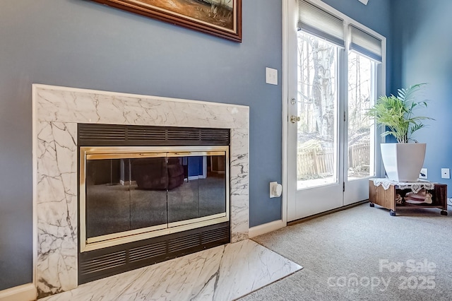 doorway to outside featuring baseboards, carpet flooring, a high end fireplace, and a healthy amount of sunlight