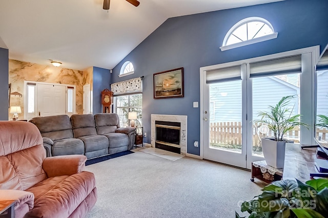 living area with a high end fireplace, light carpet, ceiling fan, high vaulted ceiling, and baseboards