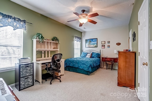 bedroom with light carpet, multiple windows, a ceiling fan, and a textured ceiling