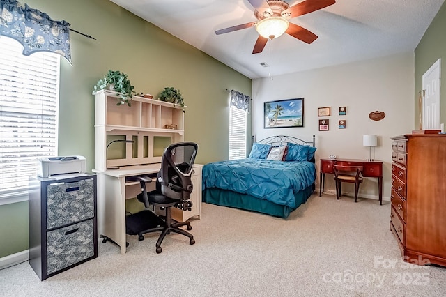 bedroom featuring baseboards, ceiling fan, multiple windows, and light colored carpet