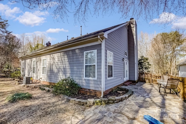 view of property exterior featuring central AC unit, a chimney, a patio area, and fence