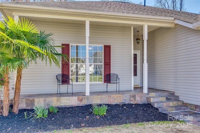 view of exterior entry featuring a porch and a shingled roof