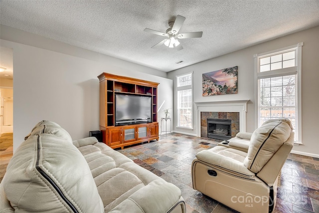 living area featuring a healthy amount of sunlight, stone tile floors, a fireplace, and baseboards