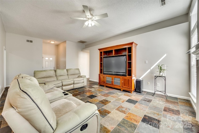 living area featuring stone finish flooring, visible vents, and baseboards