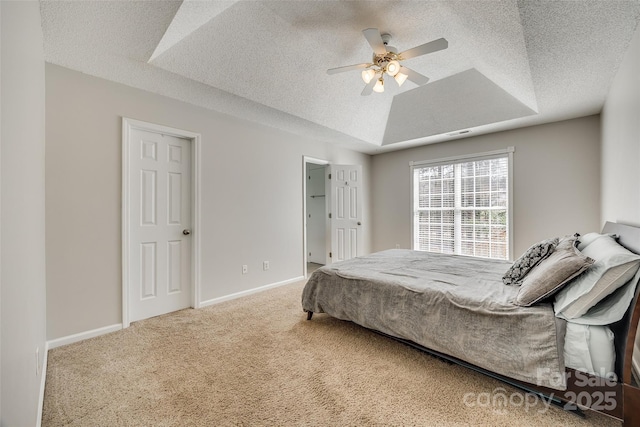 bedroom with a textured ceiling, baseboards, a raised ceiling, and carpet flooring