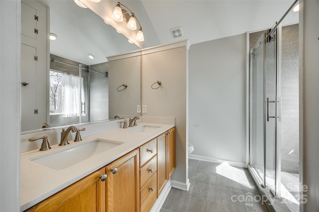 bathroom with double vanity, a shower stall, toilet, and a sink