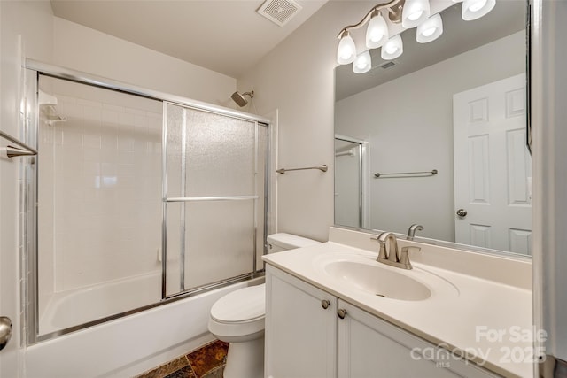 bathroom featuring toilet, bath / shower combo with glass door, vanity, and visible vents