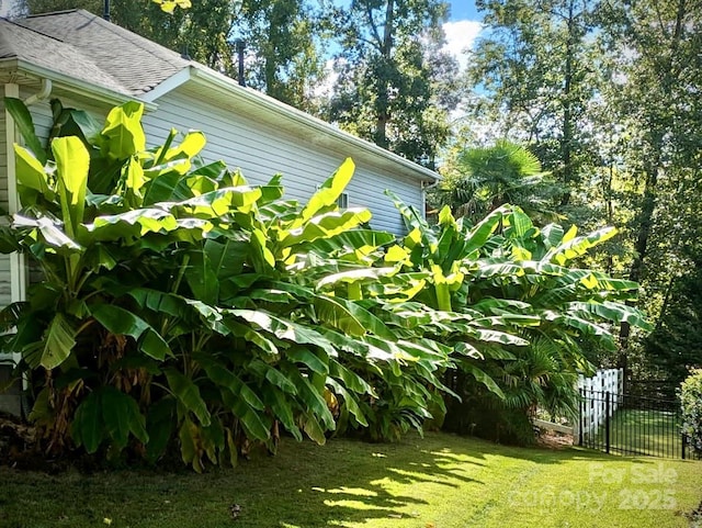 exterior space featuring a shingled roof, a lawn, and fence